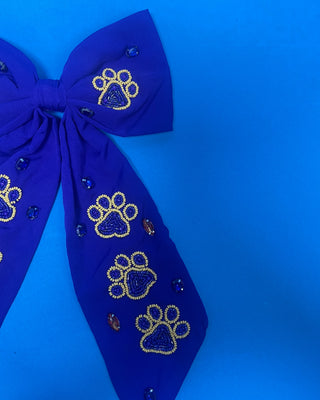 Purple LSU statement hair bow with hand-beaded gold and purple tiger paw prints, rhinestone accents, long tails, and a French barrette clip.