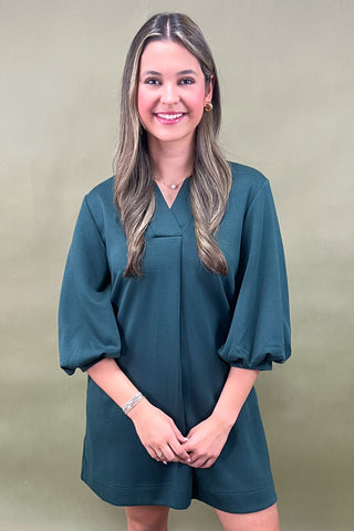 Woman wearing a teal dress against a green background
