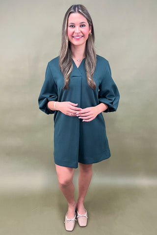 Woman wearing a teal dress against a green background