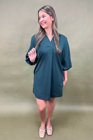 Woman wearing a teal dress against a green background