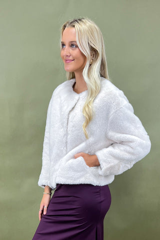 Woman wearing a white fluffy jacket against a green background