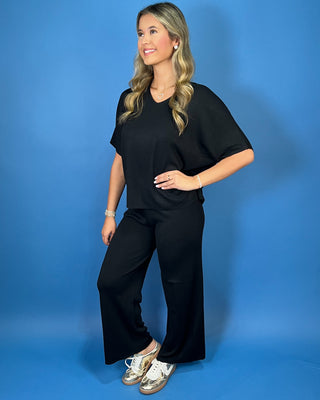 Black two-piece matching set featuring a relaxed V-neck short sleeve top and coordinating straight-leg pants for an effortless, comfortable everyday look.