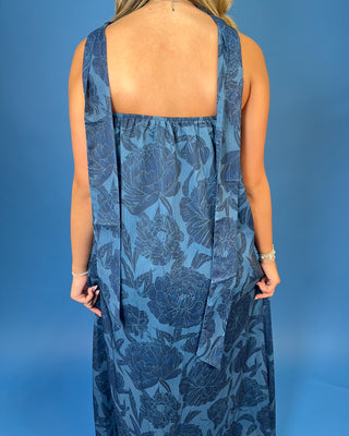 a sleeveless halter-neck maxi dress with a dark blue floral pattern on a medium blue background