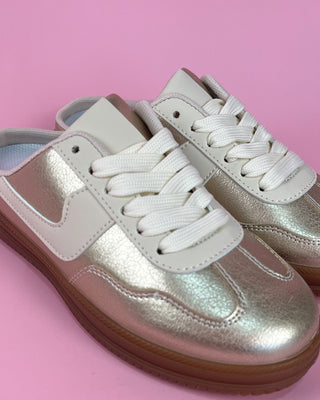 Pair of silver sneakers with white laces on a pink background