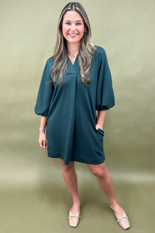 Woman wearing a teal dress against a green background