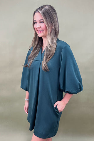 Woman wearing a teal dress against a green background