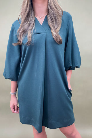 Woman wearing a teal dress against a green background