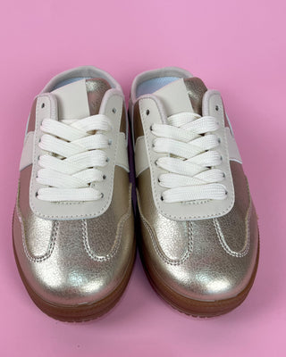 Pair of silver metallic sneakers with white laces on a pink background
