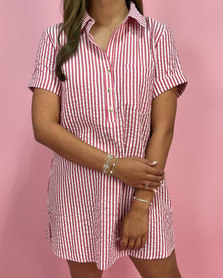 Person wearing a red and white checkered dress against a pink background