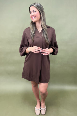 Woman wearing a brown dress against a green background