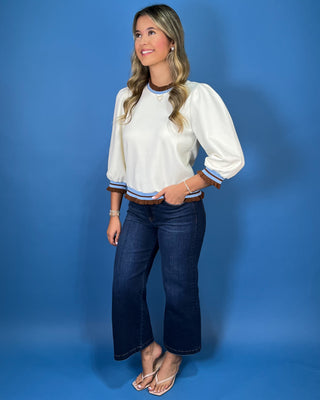Cream puff sleeve top with light blue and brown striped trim, finished with feminine brown ruffle details at the neckline, cuffs, and hem.