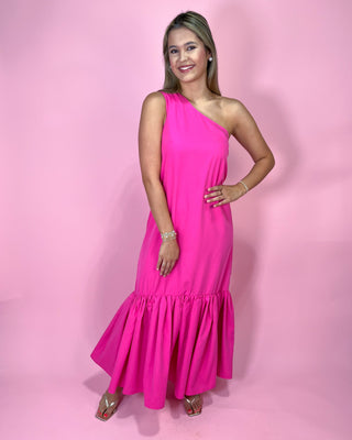 Woman wearing a bright pink one-shoulder dress against a pink background