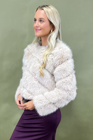 Woman wearing a fluffy white jacket against a green background