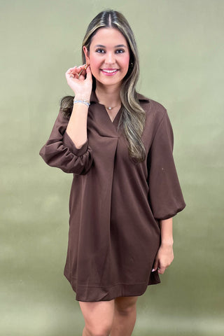 Woman wearing a brown dress against a green background