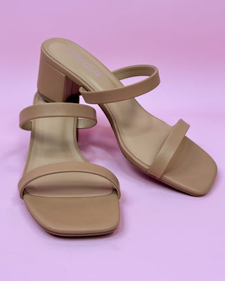 Beige high-heeled sandals on a pink background