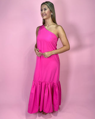 Woman wearing a bright pink one-shoulder dress against a pink background