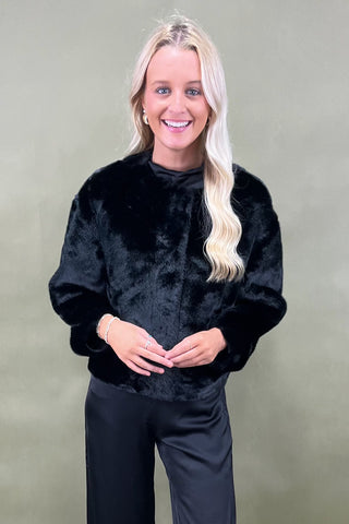Woman wearing a black outfit against a plain background