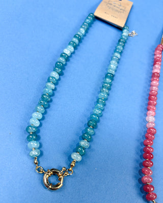 A beaded necklace with alternating light blue and medium teal-blue round beads