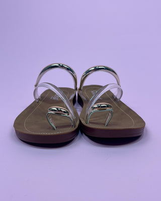 Pair of sandals with clear straps on a light purple background