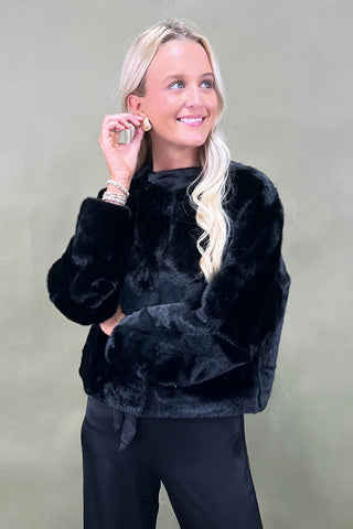 Woman wearing a black fluffy sweater against a plain background