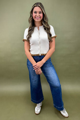 Woman wearing a white blouse and blue jeans against a green background