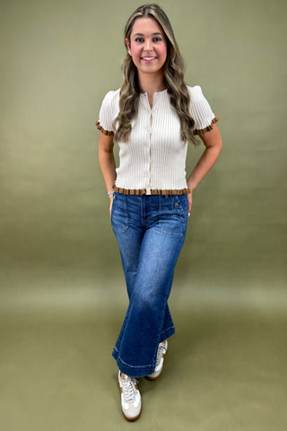 Woman wearing a white blouse and blue jeans against a green background
