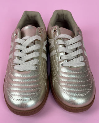 Gold metallic lace-up sneaker with white accents and gum sole on pink background