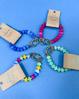 Four beaded stretch bracelets arranged in a circle, The bracelets are in blue, pink, yellow, and mint green bead combinations.