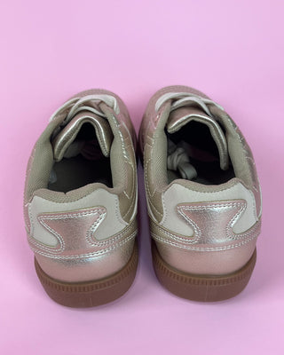 Gold metallic lace-up sneaker with white accents and gum sole on pink background