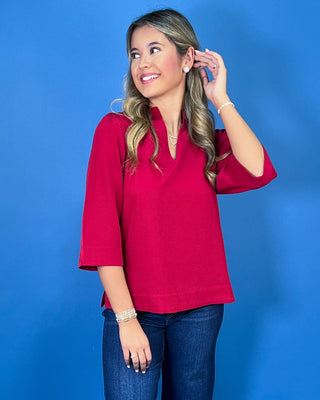 Red textured blouse featuring a split V-neckline with a structured collar, three-quarter bell sleeves, and an easy relaxed fit.