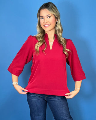 Red textured blouse featuring a split V-neckline with a structured collar, three-quarter bell sleeves, and an easy relaxed fit.
