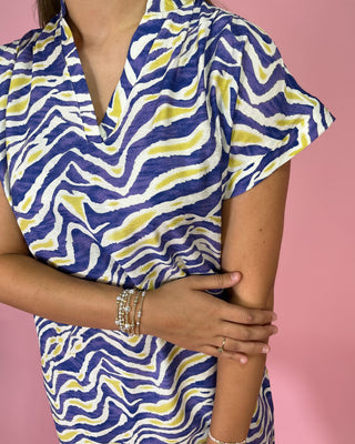 Person wearing a blue and yellow patterned dress against a pink background