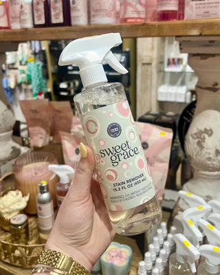 Hand holding a bottle of 'sweet grace' stain remover product in a store setting