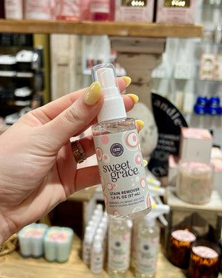 Hand holding a bottle of 'sweet grace' stain remover in a store setting