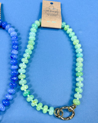 A beaded baby necklace with light green and mint blue round beads