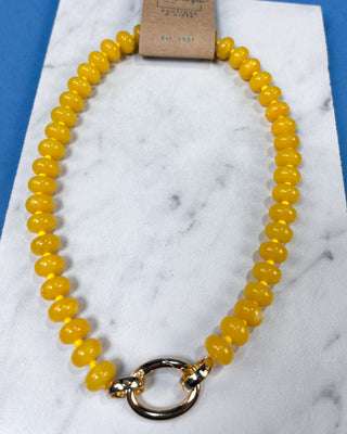 A yellow beaded necklace with a gold-toned ring clasp