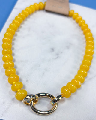 A yellow beaded necklace with a polished gold-tone split ring clasp