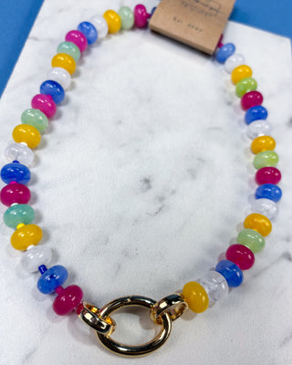 A colorful beaded necklace with translucent round beads in pink, blue, yellow, green, and white