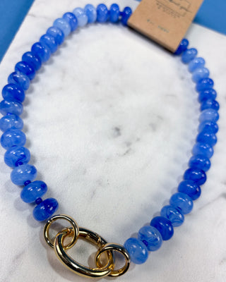 A beaded necklace made of translucent blue gemstone beads with a polished gold clasp