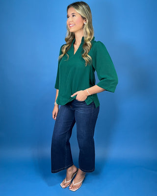Emerald green textured blouse featuring a split V-neckline with a pleated stand collar, three-quarter sleeves, and an easy relaxed fit.
