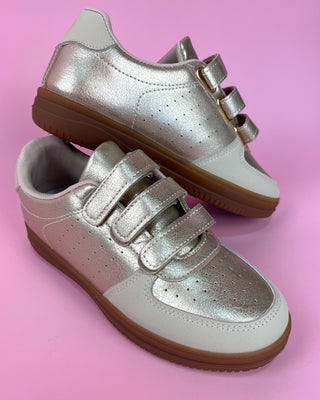 Silver metallic triple-strap sneaker with white accents and gum sole on pink background