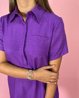 Person wearing a purple shirt with a pink background
