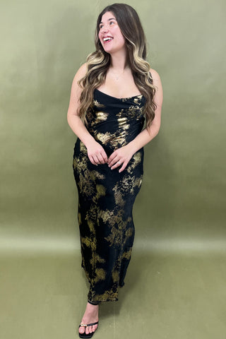 Woman wearing a black and gold dress against a green background