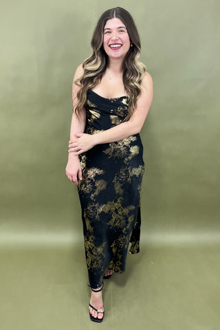 Woman wearing a black floral dress against a green background