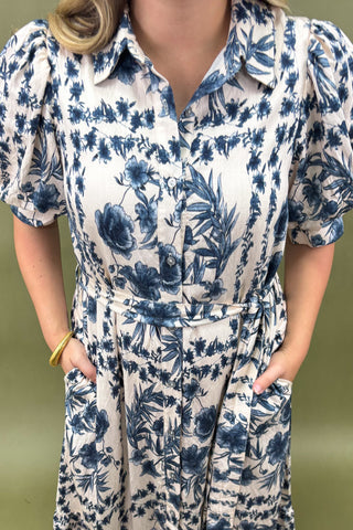Person wearing a blue floral dress against a green background