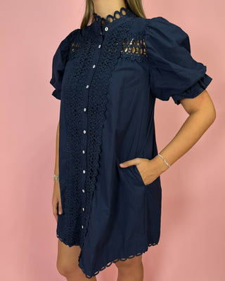 Navy blue dress with lace details on a pink background