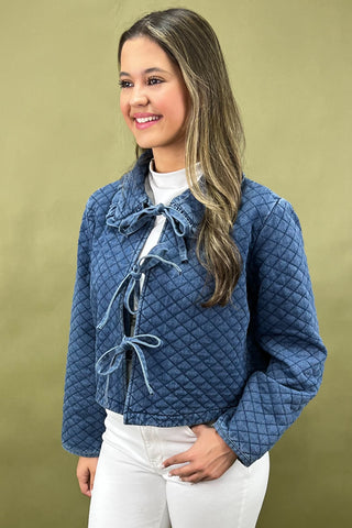 Woman wearing a blue quilted jacket against a beige background