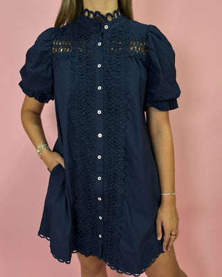 Navy blue dress with lace detailing on a pink background