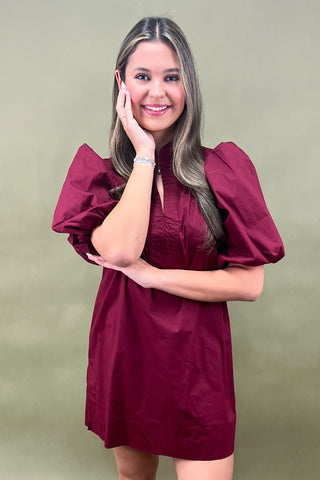 Woman wearing a burgundy dress against a green background