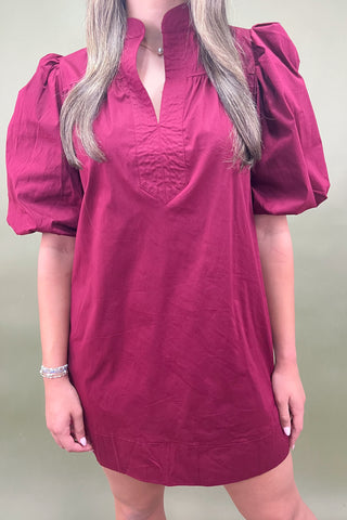 Person wearing a pink dress with puff sleeves against a plain background